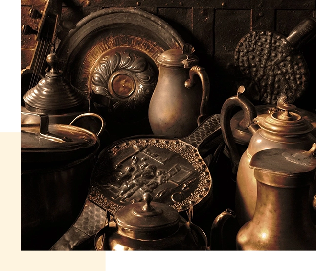 A collection of antique household items, including pots and utensils, displayed on a table for sale.