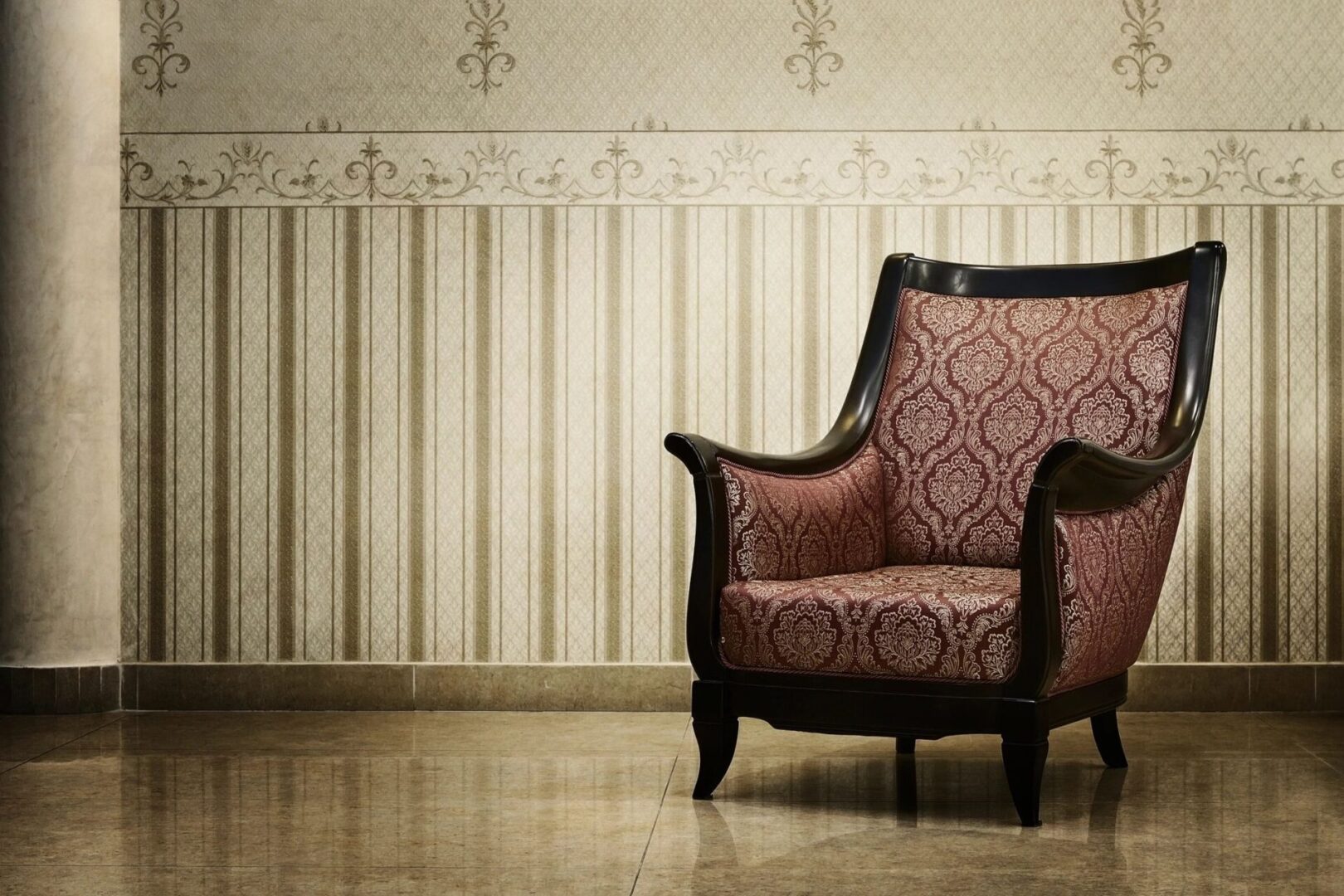 An old chair in a room with a patterned wall.